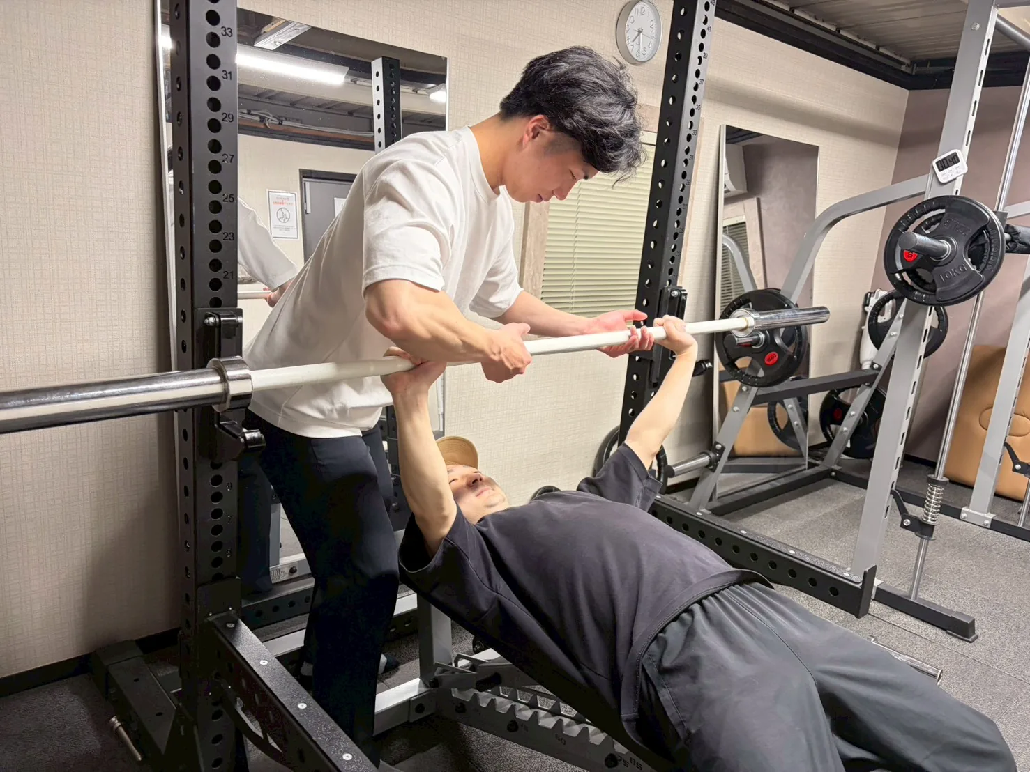 スクワットのフォームをトレーナーが補助している様子