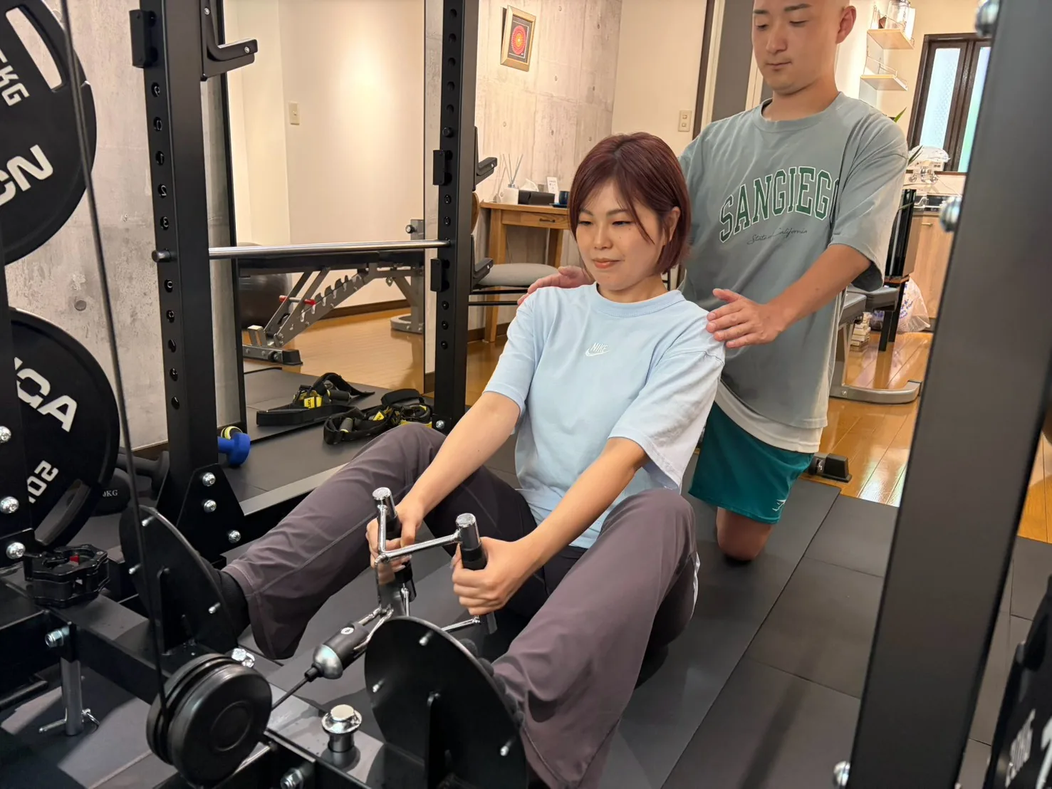 シーテッドロウの姿勢をトレーナーが手で補助している様子